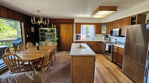 Eine Küche mit Holzausstattung, einem Edelstahlkühlschrank und einem Essbereich mit Tisch und Stühlen.