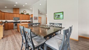A modern kitchen with wooden cabinets, a microwave, and a dining area with a large table and chairs.