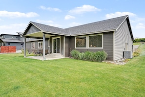 A modern house with a covered patio, a well-maintained lawn, and a clear sky. - Columbia Riverfront 4BR | Near Lake Chelan & Golf (Orondo)