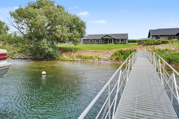 A bridge leading to a house by a river.
