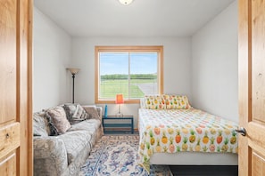 A bedroom with a bed, a couch, a lamp, and a window with blinds. - Columbia Riverfront 4BR | Near Lake Chelan & Golf (Orondo)