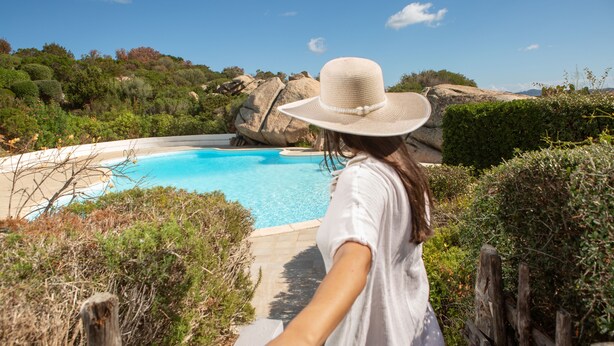 Eine Person geht auf ein Schwimmbecken zu, umgeben von einer natürlichen Landschaft.