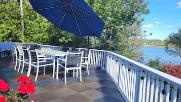 An outdoor deck with a table and chairs, overlooking a body of water.