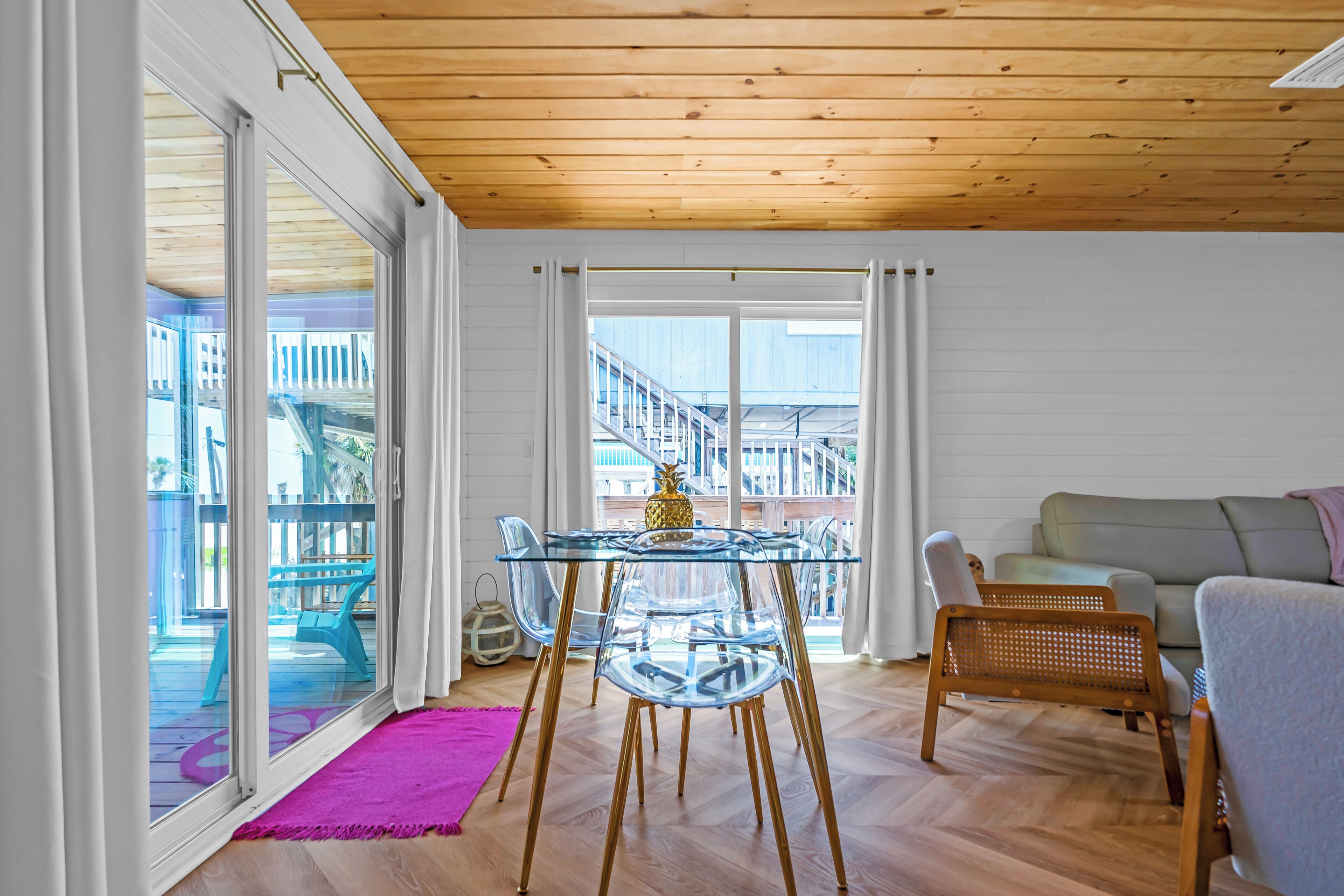 Une pièce avec une table à manger en verre, des chaises en bois, un canapé et un balcon avec vue.