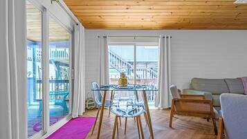 Une pièce avec une table à manger en verre, des chaises en bois, un canapé et un balcon avec vue.