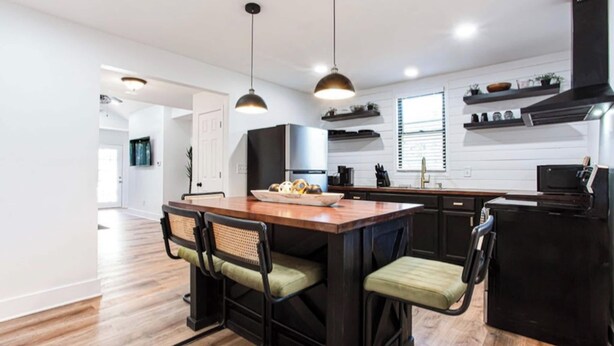 A modern kitchen with a central island, pendant lighting, and black cabinetry. - 2 Bedroom Modern Lake House Close to Midtown (College Park)