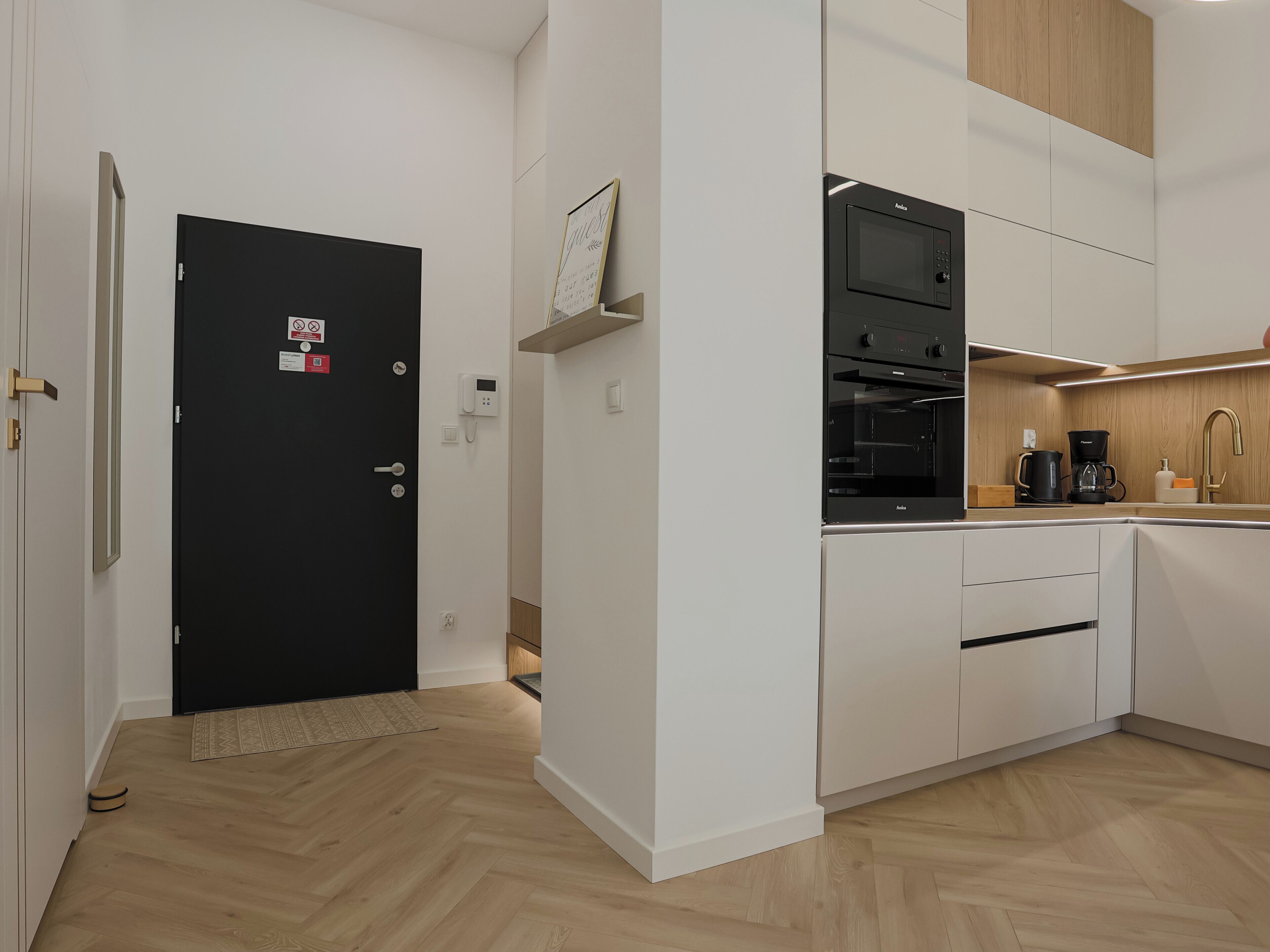 Een moderne keuken met witte kastjes, een zwarte oven en een koffiezetapparaat.