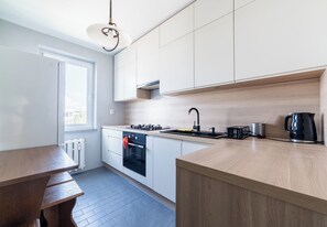 A modern kitchen with white cabinets, a wooden countertop, a built-in oven, and a kettle. - Osiedle Batorego Colorful Apartment (Poznań)