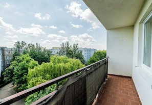 A balcony with a view of a cityscape, a brick floor, and a railing. - Osiedle Batorego Colorful Apartment (Poznań)