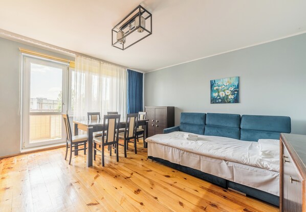 A room with a bed, a desk, chairs, a cabinet, and a painting on the wall. - Osiedle Batorego Colorful Apartment (Poznań)