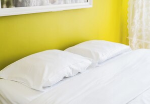 A bed with white bedding in a room with a yellow wall. - Osiedle Batorego Colorful Apartment (Poznań)