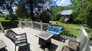 A wooden deck with wicker furniture, a table, and a bench.