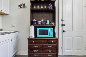 Una cocina con microondas, armarios, un aparador de madera y una puerta blanca.