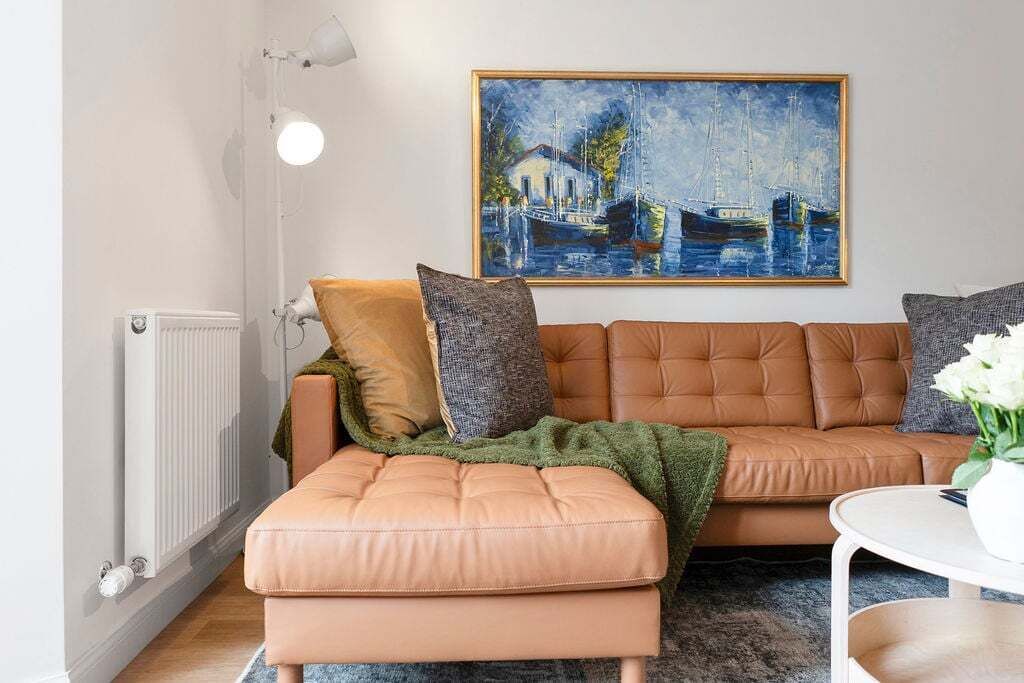 Una sala de estar con sofá, un cuadro, un radiador y una lámpara.