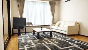 A living room with a television, sofa, coffee table, and patterned rug. - Minami Ward, Sapporo—10 or more people / Free shuttle service available / Perfect for groups and families with children! Free parking for 4 cars / We can arrange rental cars! (札幌市minami-ku,fujino)