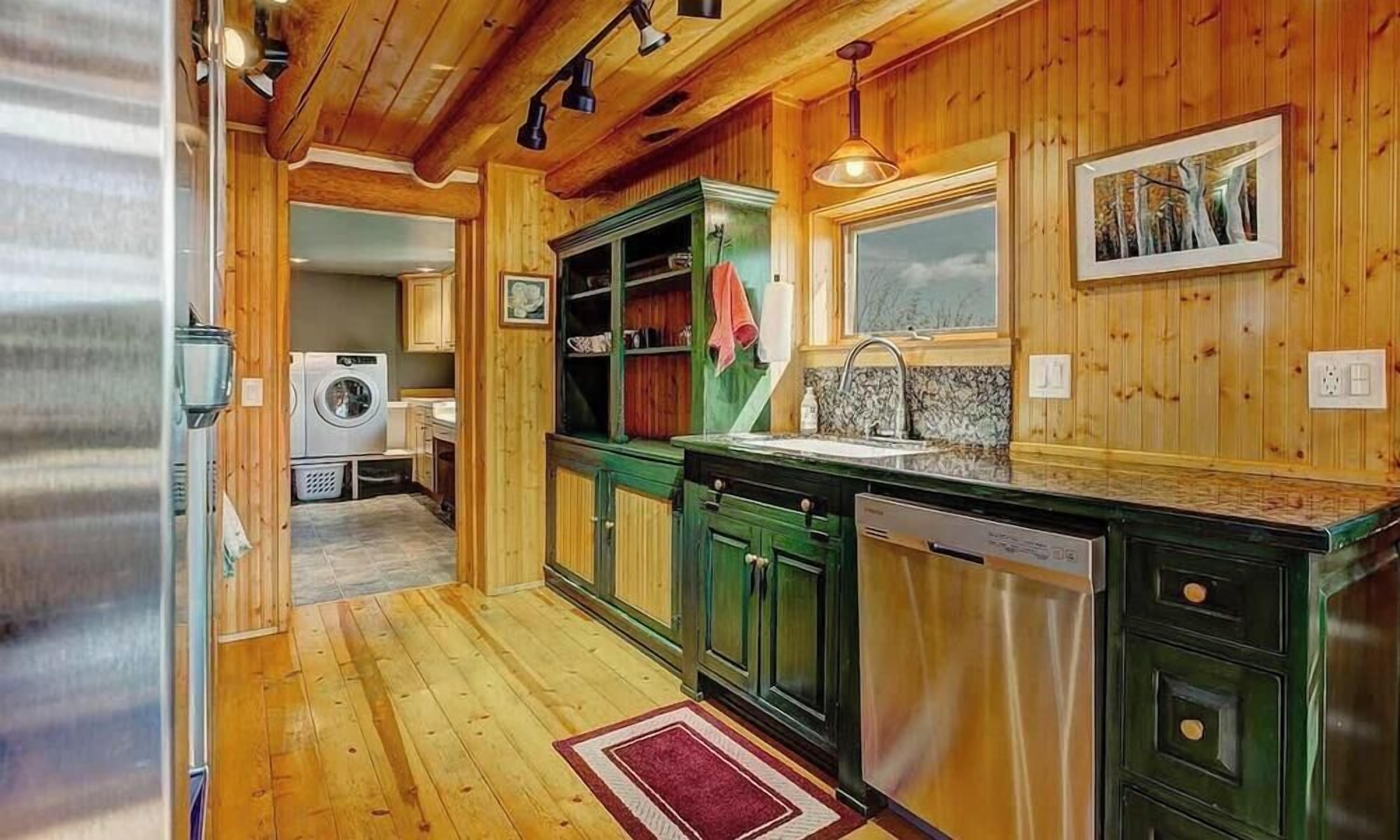Une cuisine compacte avec des meubles en bois, un lave-linge encastré et une fenêtre.