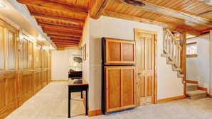 A hallway with wooden paneling, a double-door cabinet, and a staircase. - Range View on the Rocks | Log Home | 360 Mtn Views (Estes Park)