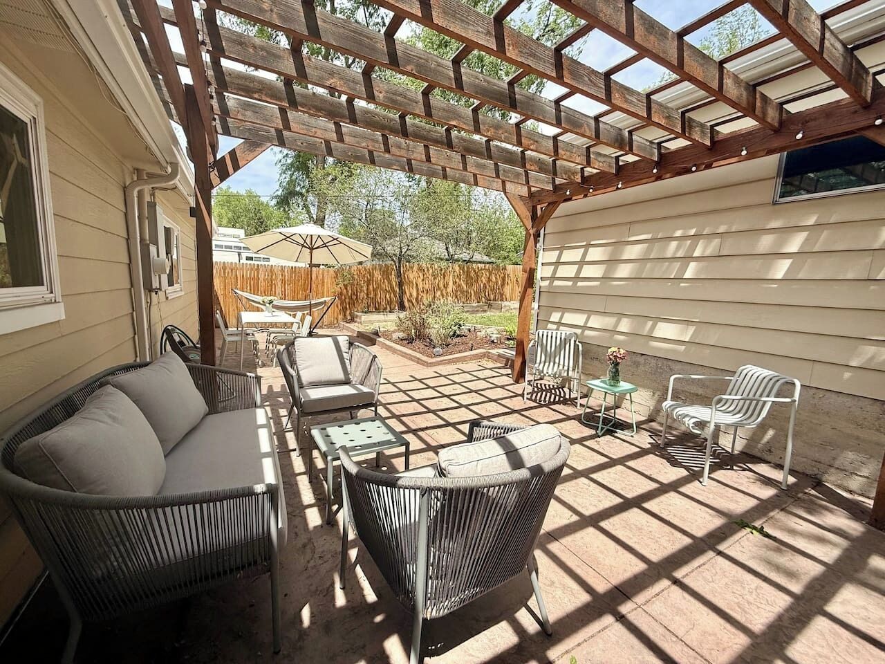 A covered patio with wicker furniture, a small table, and a chair.
