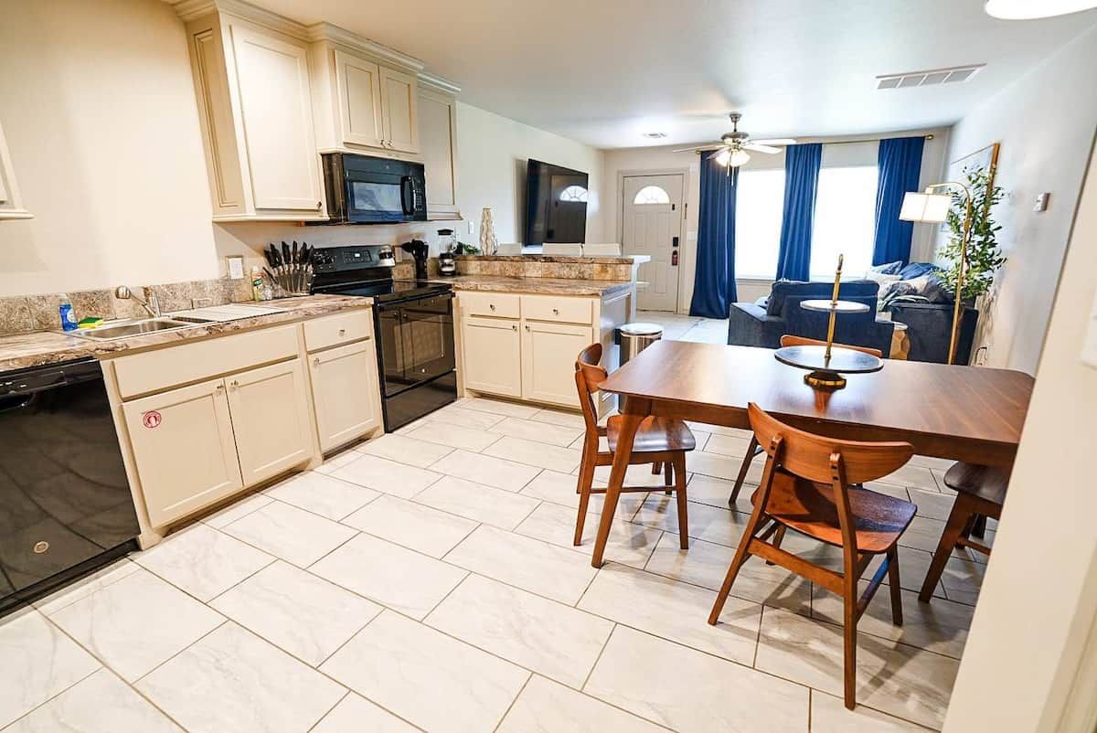 A modern kitchen with a dining area, a flat-screen TV, and a sofa in the living room.