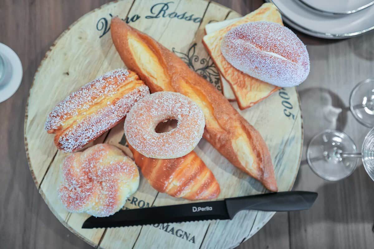 A wooden table with a plate of pastries, a knife, and wine glasses.