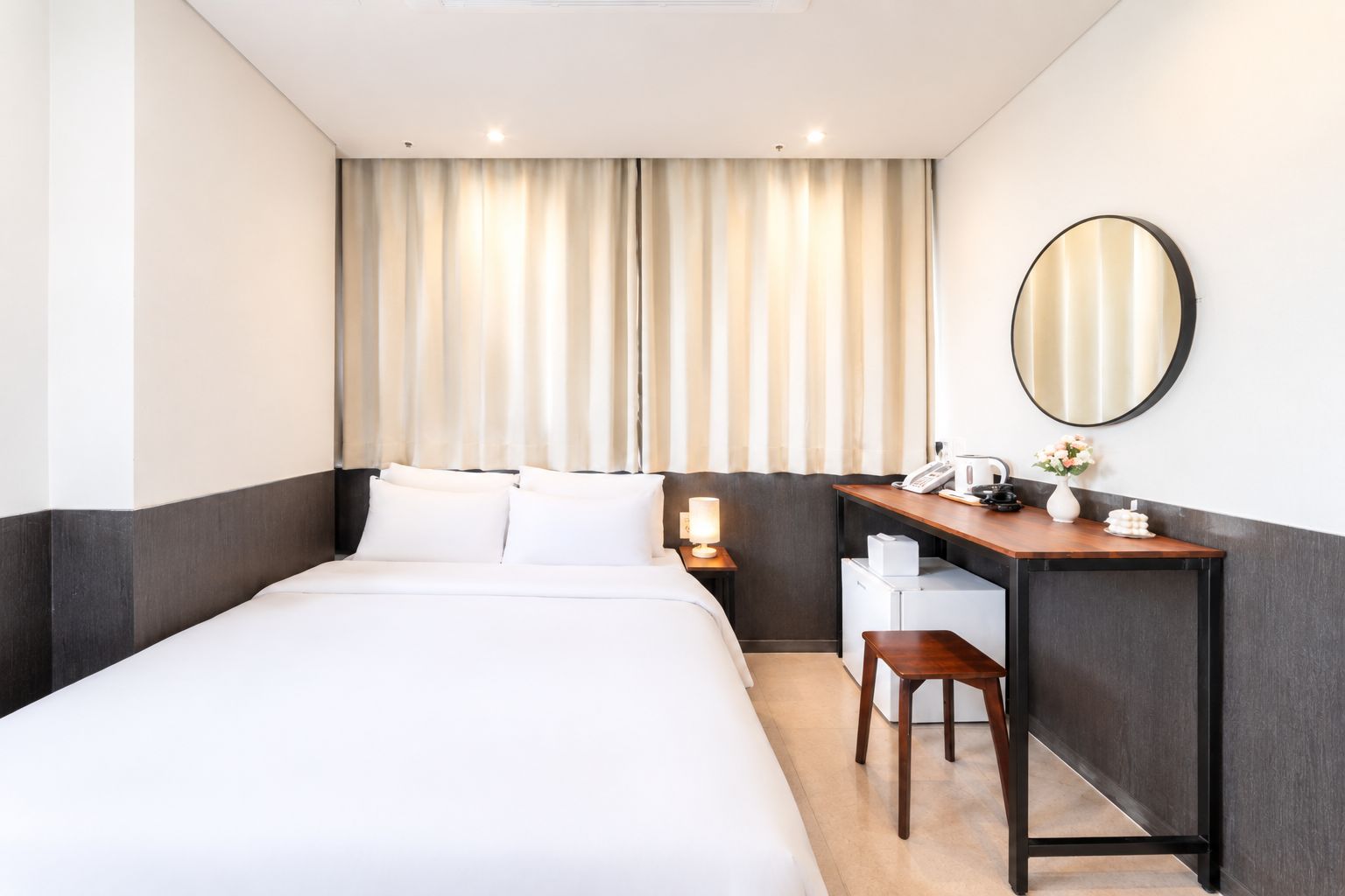 Une chambre d’hôtel avec un lit, un bureau, une chaise et un miroir.
