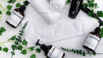 A neatly arranged set of toiletries including a towel, a hairdryer, and bottles of shampoo and conditioner.