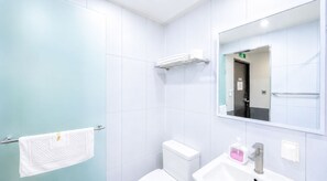 A modern bathroom with a toilet, sink, and mirror. - The Stay Korea (Seoul)