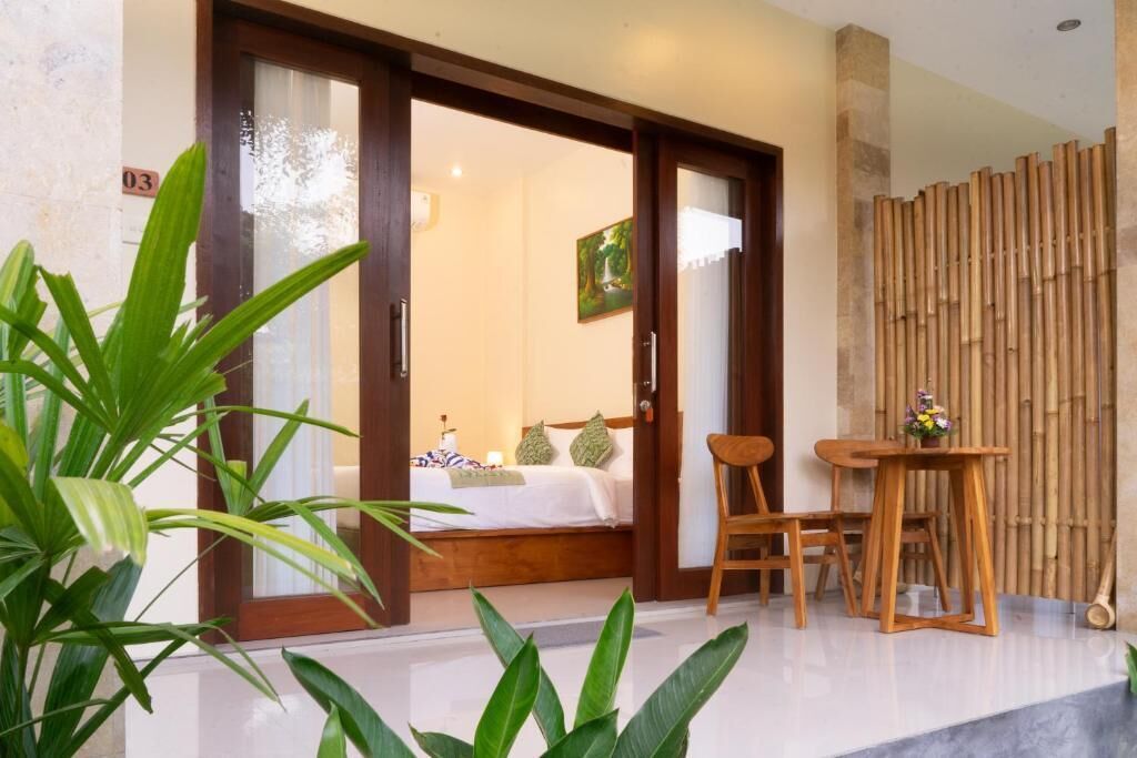 A hotel room with a bed, a chair, a table, and a bamboo screen.