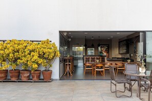 An open-plan living area with a kitchen, dining space, and a large potted plant. - Superior Triple Suite | Shared Outdoor Pool, Sun Terrace & Free Parking (Araçatuba)