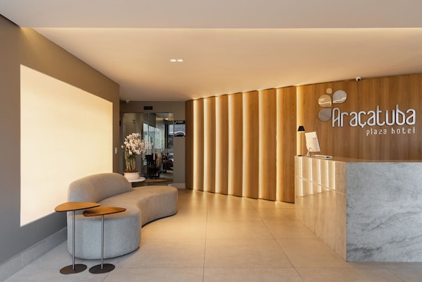 A modern reception area with a curved sofa, a reception desk, and a wooden panel wall.