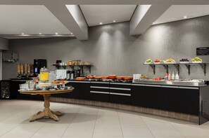 Cuina moderna amb una illa central, electrodomèstics integrats i diversos aliments exposats a les prestatgeries.