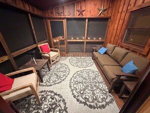 A cozy room with a wooden interior, a sofa, a chair, a small table, and a patterned rug.