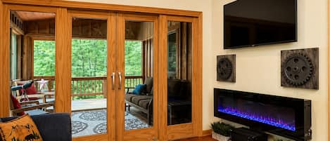 Una sala de estar con televisor, puertas correderas de madera y chimenea.