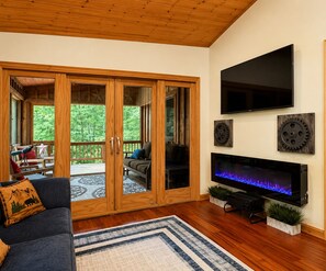 Een woonkamer met een televisie, houten schuifdeuren en een open haard.