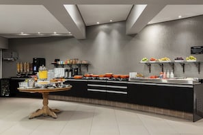 Una cocina moderna con una isla central, electrodomésticos integrados y diversos alimentos exhibidos en estantes.