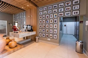 Un área de recepción con una pared de fotos enmarcadas, un mostrador de recepción y un cubo de basura.