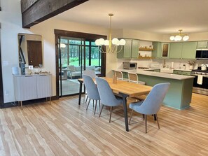 Eine moderne Küche mit Essbereich, ausgestattet mit einem Holztisch, grauen Stühlen und einer zentralen Kochinsel.