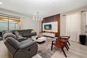 Ein modernes Wohnzimmer mit Ecksofa, Couchtisch, Wand-Fernseher und Essbereich mit Holzkästen.