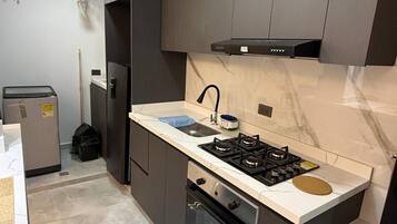 Una cocina moderna con armarios oscuros, estufa a gas, horno empotrado y encimera de mármol.