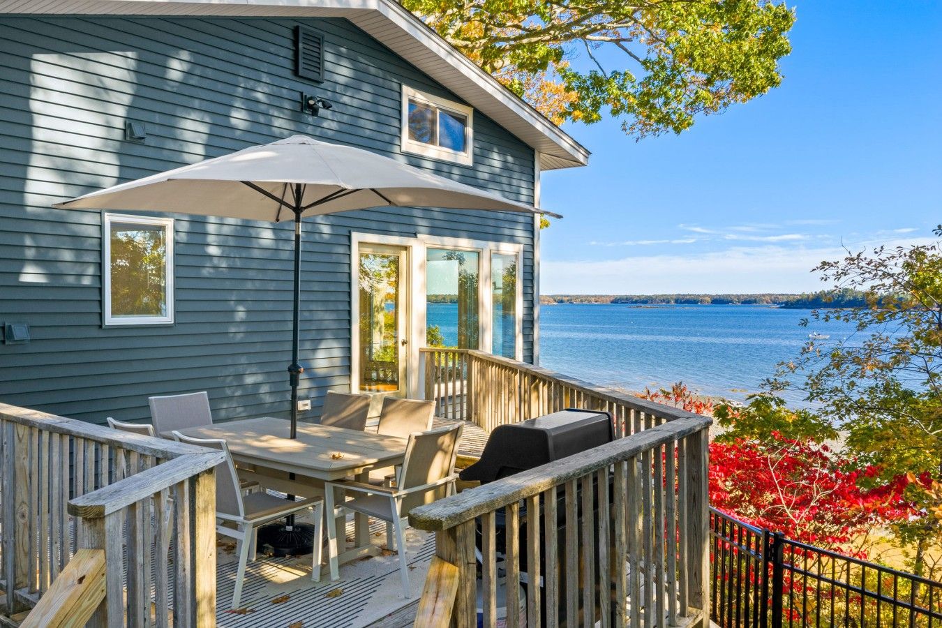 A house with a deck, outdoor furniture, and a view of a lake.