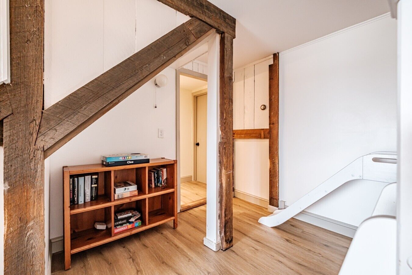 A room with a wooden bookshelf, a white door, and a staircase.