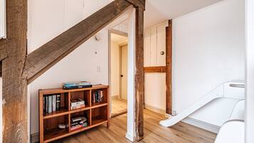 A room with a wooden bookshelf, a white door, and a staircase.