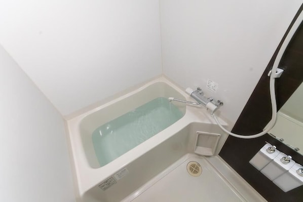 Un baño pequeño y blanco con bañera, inodoro y lavamanos.