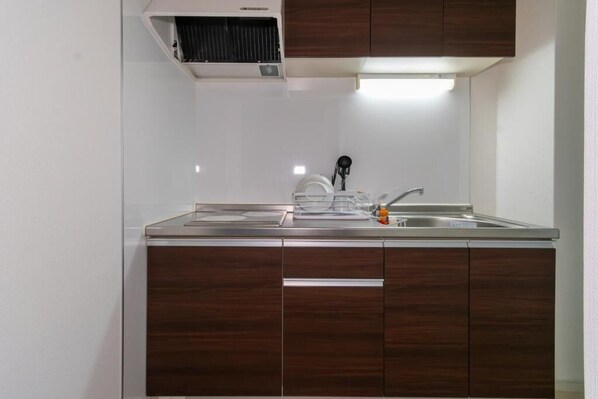 Una cocina con encimera de acero inoxidable, un lavamanos y armarios de madera.