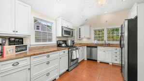 Una cocina moderna con armarios blancos, un refrigerador de acero inoxidable, un microondas y una estufa.