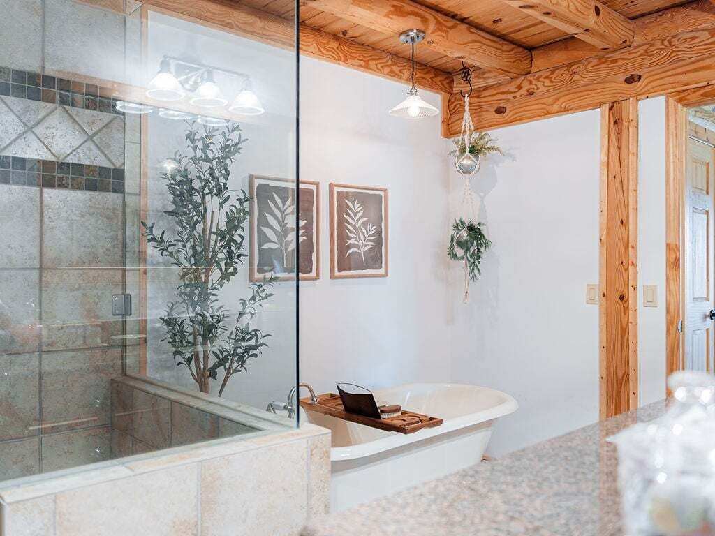 Une salle de bain moderne avec une baignoire sur pieds, une douche en verre et des poutres en bois au plafond.