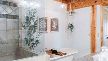 Une salle de bain moderne avec une baignoire sur pieds, une douche en verre et des poutres en bois au plafond.