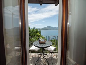 Varanda com mesa e cadeiras, vista para um lago e montanhas.
