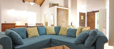 A living room with a blue sectional sofa, wooden coffee table, and a ceiling with exposed beams.