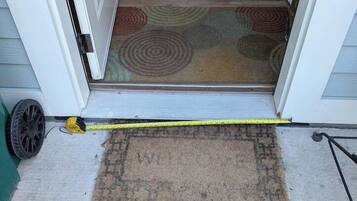 A doorway leading to a room with a patterned rug and a measuring tape on the floor.